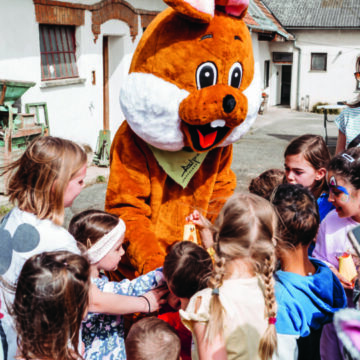 Osterhase-Maskottchen umringt von begeisterten Kindern beim Oster Special Osterhase-Maskottchen umringt von begeisterten Kindern beim Oster Special